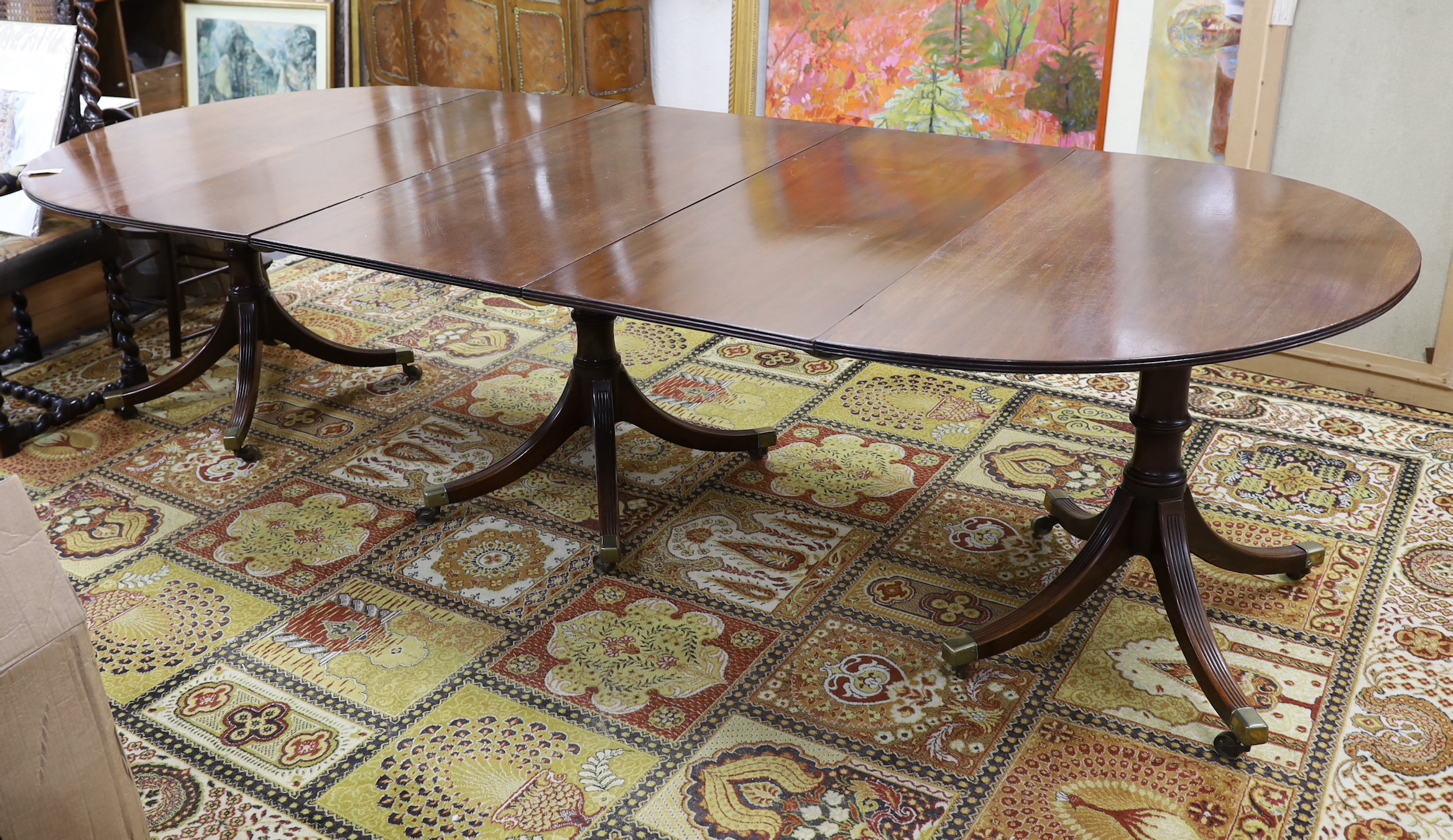 A George III style mahogany triple pillar D end extending dining table in the manner of Gillows
